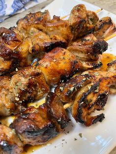 chicken skewers with sauce and herbs on a white plate