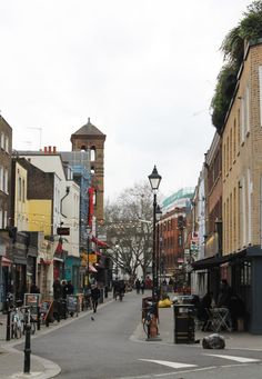 an empty city street with people walking and sitting on the benches in front of buildings