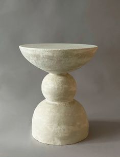 a large white vase sitting on top of a table next to a gray wall and floor