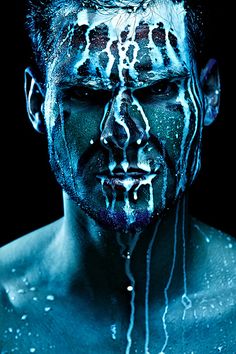 a man with blue paint on his face and body is covered in white icing