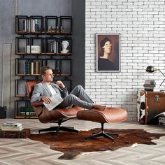 a man laying on top of a chair in a living room next to a book shelf