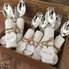 a box filled with silverware sitting on top of a wooden table covered in tags