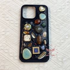 a cell phone case with many different stones and jewels in it on a white surface