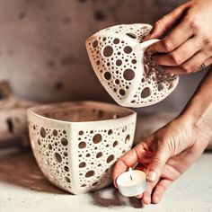 a person is holding a tea light holder and pouring it into a cup with a candle