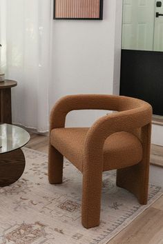 a brown chair sitting on top of a wooden floor next to a glass coffee table