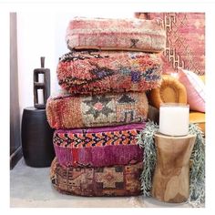 a pile of colorful rugs sitting on top of a floor next to a candle