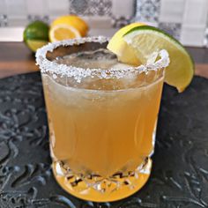 a close up of a drink on a table with lemons and limes in the background