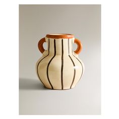 a white and brown striped vase sitting on top of a table