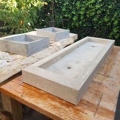 two concrete sinks sitting on top of a wooden table