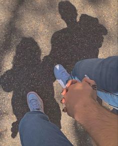 two people standing next to each other with their shadows on the ground in front of them