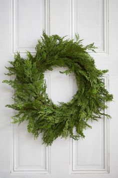 a close up of a wreath on a door with white paint and wood paneling