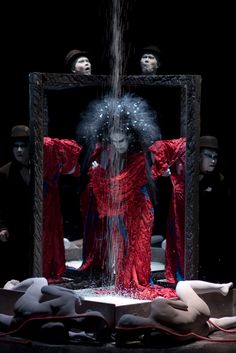 a woman is standing in front of a mirror with water coming out of it