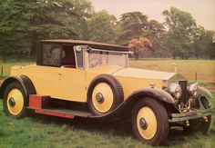 an old yellow car is parked in the grass