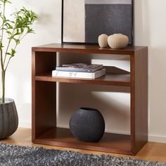 a vase and some books on a shelf next to a plant in a living room