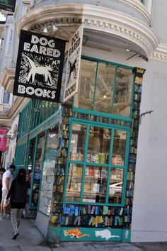 people are walking past a book store on the side of the street in front of it