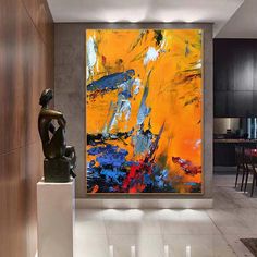 an abstract painting hangs on the wall next to a statue in a modern living room