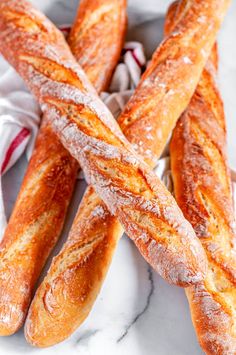 several loaves of bread sitting on top of a white table cloth covered in powdered sugar