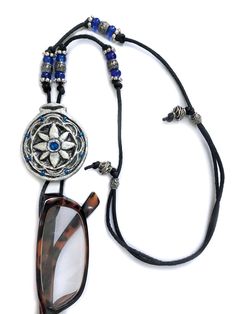 Hand-crafted silver and blue-colored flower pendant necklace painted with acrylics and decorated with blue Swarovski crystal bead, glass seed beads and fine ink details. The pendant is 1-3/4 inches in diameter and is protected with a polyurethane coating. The necklace has a unique retractable loop that holds eyeglasses/sunglasses, is 14 inches long and adjustable. Shipping: Within US - FREE Outside US - Ebay Global Shipping Program ﻿ IF YOU LIKE WHAT SEE PLEASE FOLLOW ME AS A SELLER. Adjustable Long Glass Necklace, Adjustable Blue Glasses Chains With Colorful Beads, Adjustable Blue Multi-strand Beaded Necklace, Blue Glass Necklaces With Adjustable Chain, Nickel-free Adjustable Glass Necklaces, Glasses Strap, Sunglasses Holder, Sunglass Holder, Flower Pendant Necklace