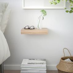 a stack of books sitting on top of a wooden shelf next to a basket and plant