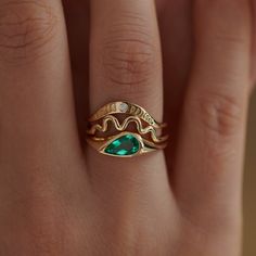 a woman's hand with a gold ring on it and an emerald stone in the middle