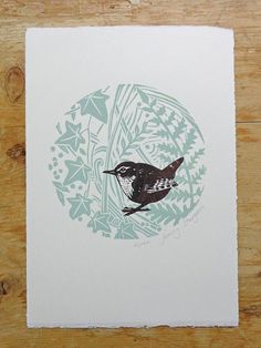 a bird sitting on top of a piece of paper next to a wooden table covered in leaves