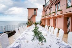 a long table is set with white linens and place settings