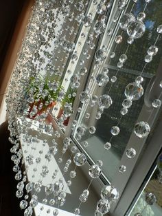 a window with lots of bubbles hanging from it's side and a potted plant in the corner