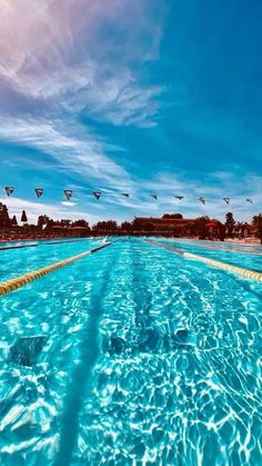 an empty swimming pool with clear blue water and birds flying in the sky above it