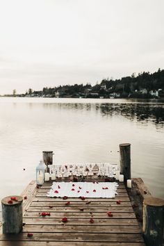 a wooden dock with flowers and candles on it that says mr and mrs married next to the water