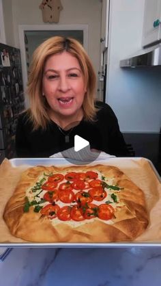 a woman holding up a pizza in front of her face with tomatoes on the crust