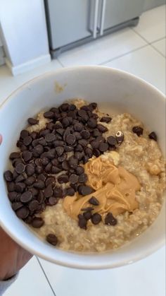 a bowl of oatmeal with chocolate chips and peanut butter in it, being held by someone