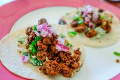 two tacos with meat and onions on a plate