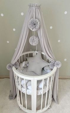 a baby crib with white polka dots on the wall and grey drapes over it