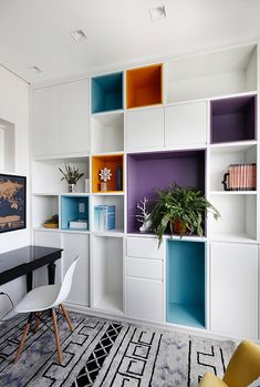 an office with colorful shelving units and a black table in the foreground is a yellow chair