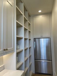 a kitchen with white cupboards and stainless steel refrigerator freezer next to it's built - in shelving