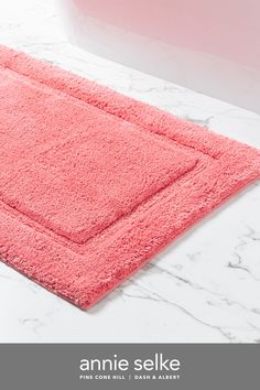 a pink bath mat sitting on top of a white counter