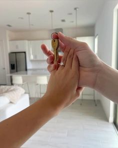 a person holding a key to another persons hand in front of a living room and kitchen