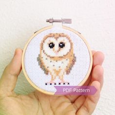 a hand holding a small cross stitch owl