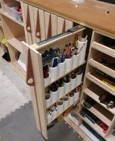 a wooden shelf filled with lots of pens and pencils