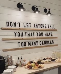 a table with plates and cups on it in front of a sign that says don't let anyone tell you that you have too many candles