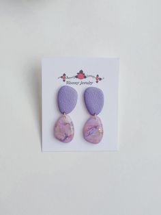 the earrings are made with purple marble and pink leather, on top of a white card