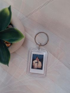 a keychain with an image of two people on it next to a potted plant