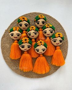 the small dolls are decorated with orange tassels and green leaves on top of each other