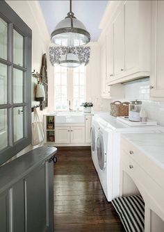 a washer and dryer sitting in a kitchen next to a window with a light hanging from the ceiling