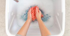 a woman is cleaning her feet in a bathtub with soap and water on the floor