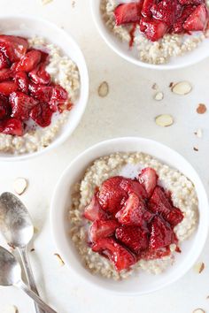 three white bowls filled with oatmeal and strawberries