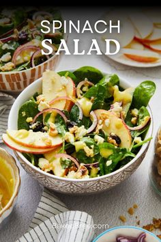 spinach salad in a bowl with apples, onions and other vegetables on the side