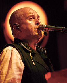 a man standing in front of a microphone with his eyes closed and looking off to the side