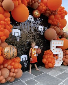 a young boy standing in front of an orange and white backdrop with basketballs on it