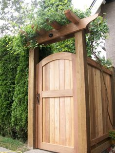 an open wooden door in the middle of a garden area with plants growing over it